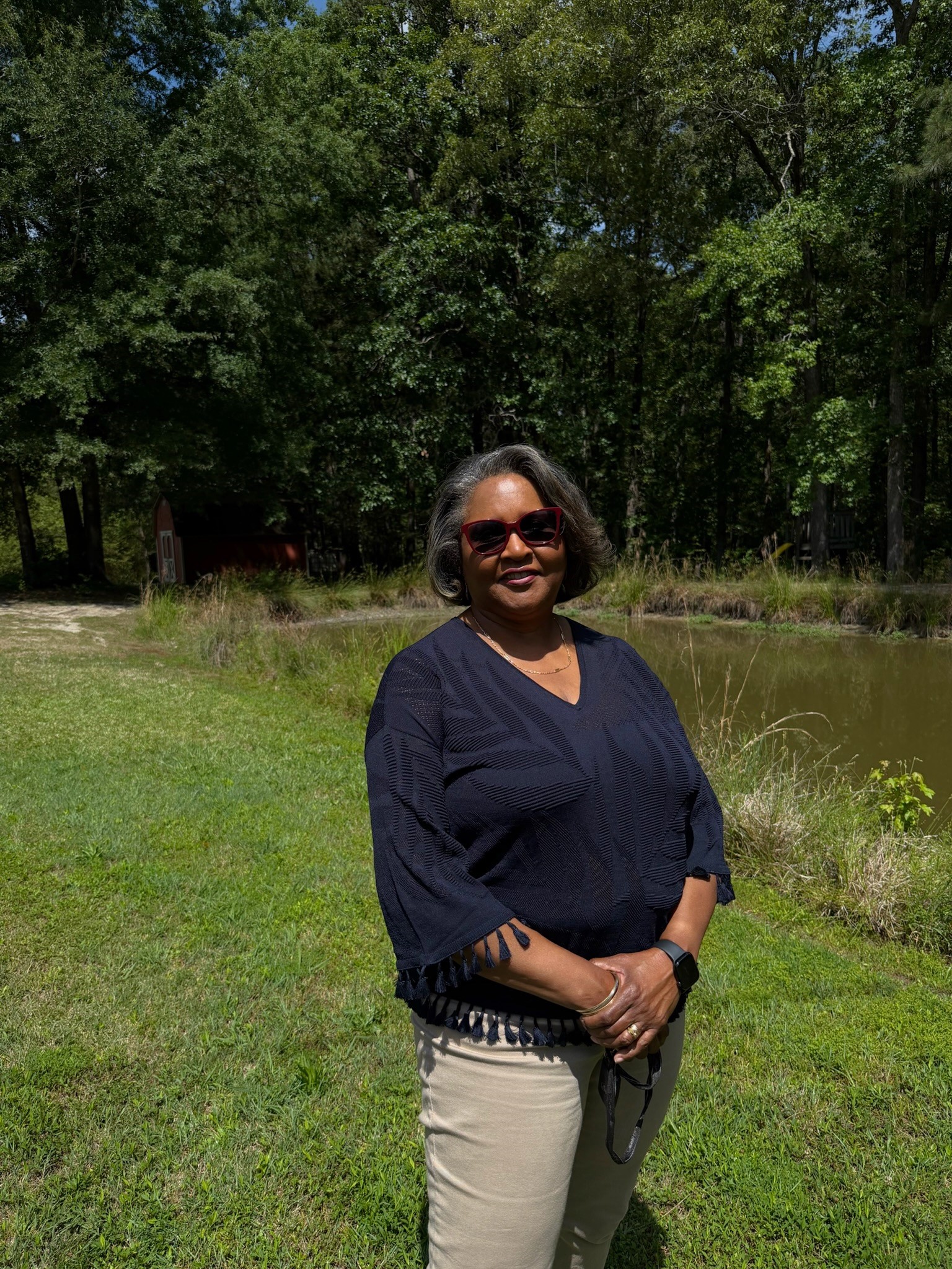 Dr. LaHoma Smith Romocki standing beside a pond on her Granville County property